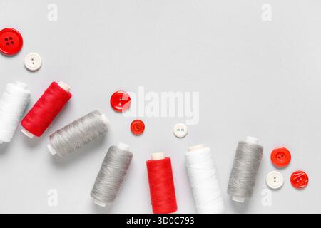 Thread spools with buttons on grey background Stock Photo