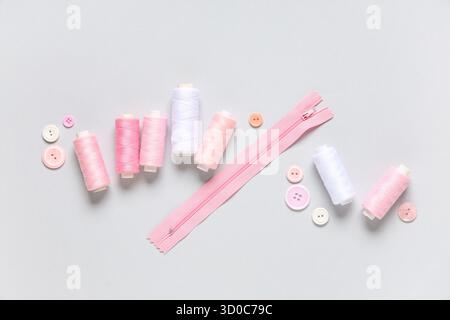 Thread spools with buttons and zipper on grey background Stock Photo