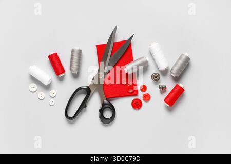 Thread spools with scissors, buttons, fabric and thimble on grey background Stock Photo
