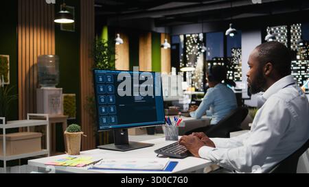 Black worker uses AI chatbot system at desktop for problem solving tasks, futuristic technology highlighting smart algorithms and machine learning. Communication and IT support. Stock Photo