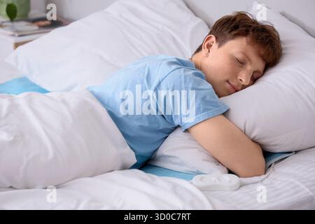 Young man sleeping on electric heating pad in bedroom Stock Photo