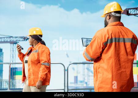 Offshore platform expert tracking oil production efficiency using tablet app. Drilling rig coworkers use device program to check equipment sensor readings, doing maintenance Stock Photo