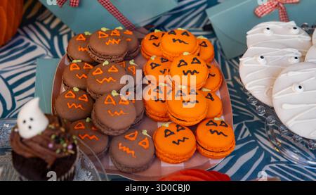 Themed desserts for the holiday table. Macarons in the shape of orange pumpkins and white mummies for Halloween Stock Photo