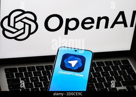 ChatGPT Atlas on phone with OpenAI wordmark on laptop screen during launch coverage. Stafford, United Kingdom, October 22, 2025 Stock Photo