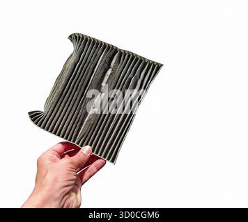 Hand holding a used and dirty car air conditioning filter on a white background. Stock Photo