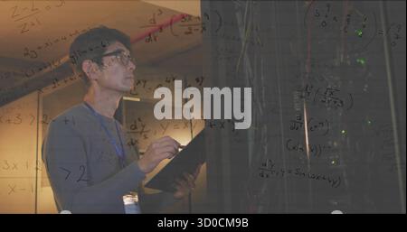 IT technician holding clipboard and inspecting server racks in data center, with LEDs, copy space Stock Photo