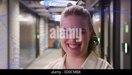 Smiling woman with striped headband standing in metallic corridor, LED panels and green lights Stock Photo