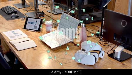 Displaying silver laptop with network icons overlay on office desk, with tablet and coffee cup Stock Photo