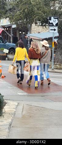 Three Friends in Boho-Cowgirl Style Walking with Shopping Bags in Wimberley, Texas Stock Photo
