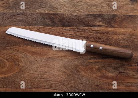 Serrated Knife with Wooden Handle on Elegant Wooden Surface Stock Photo