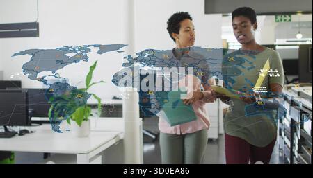 Walking two professionals reviewing document folders in open-plan office, with world map overlay Stock Photo