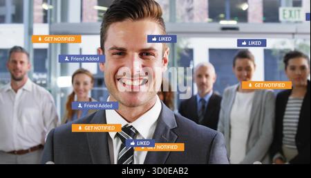 Smiling business professional standing with colleagues in office lobby with social media icons Stock Photo