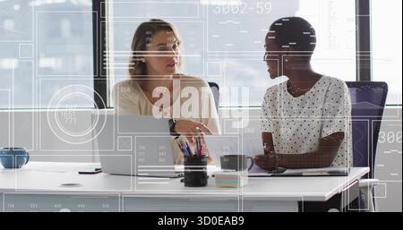 Discussing two mid adult professionals collaborating at modern office, with laptops and camera lens Stock Photo