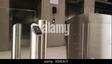 Presenting steel turnstile with touchscreen card reader in corporate lobby, with glass barriers Stock Photo