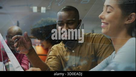 Pointing brown-shirted developer explaining interface code in open office, with glass partition Stock Photo