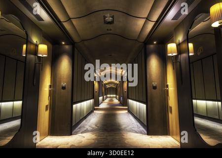Looking straight into a long dark hotel corridor Stock Photo