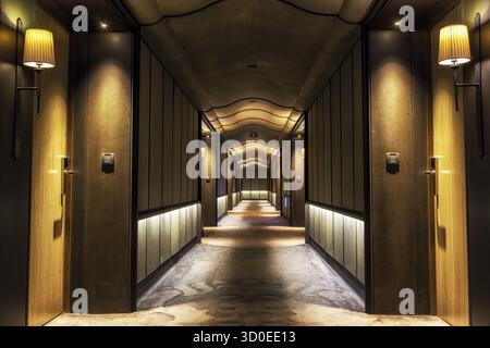Looking straight into a long dark hotel corridor Stock Photo