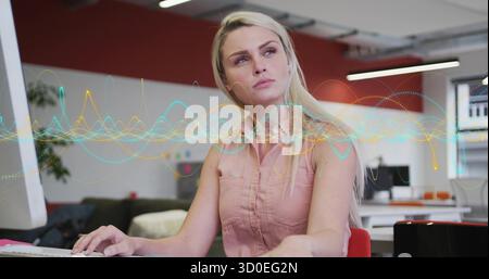 Typing woman developer entering code on keyboard at desk in open-plan office, with waveform overlay Stock Photo