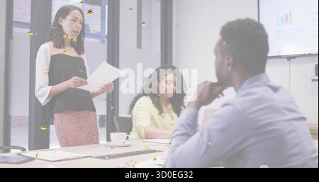 Presenting Asian woman holding papers, pointing at bar charts in conference room, with laptop Stock Photo