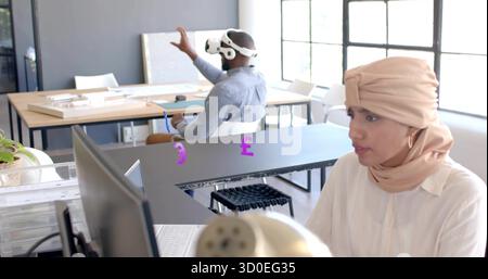 Working Asian Indian woman typing on computer at office, with VR headset, scale models, copy space Stock Photo