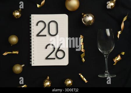 Celebratory New Year 2026 setup with notebook and glass Stock Photo