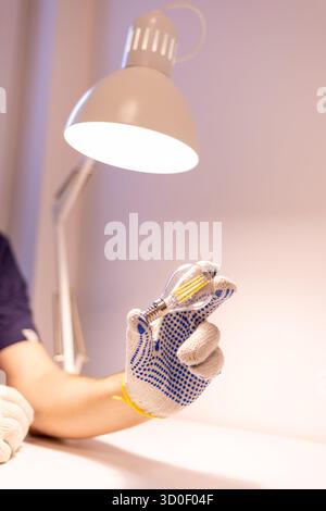 Close-up of a hand in protective glove holding filament LED bulb. apartment lightning Stock Photo