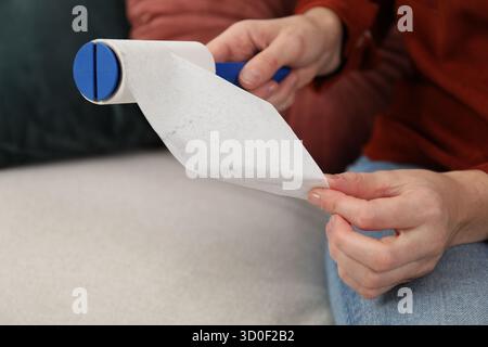 Woman removing sticky tape from lint roller at home, closeup Stock Photo