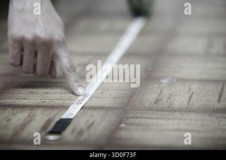 Human hands using measuring tape on a wooden surface Stock Photo