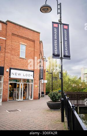 Store front view of a New Look shop in Kidderminster's Weavers Wharf area with doors open. Weavers Wharf flags hang from nearby lamp post. Stock Photo