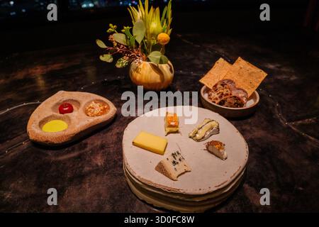 A high-angle shot captures a gourmet cheese board featuring an assortment of cheeses, crackers, and condiments in an upscale dining venue. Stock Photo