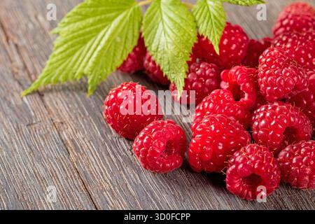 A beautiful macro shot featuring ripe raspberries with a burst of color, complemented by fresh green leaves, showcasing nature's bounty in exquisite d Stock Photo