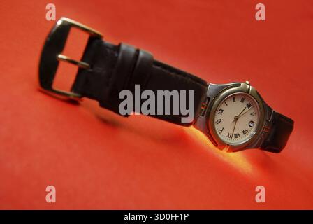 Silver watch with leather bracelet on a red background Stock Photo