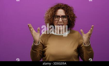 Woman rubbing eyes looking incredulous over bright pink wall wearing glasses brown sweater middle age brunette hispanic isolated setting conveying dis Stock Photo