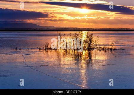 Sunset at a frozen lake a cold winter evening Stock Photo