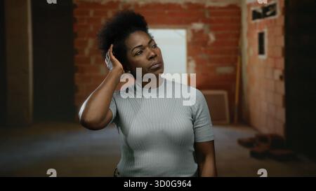 Woman contemplating in an incomplete indoor construction site wearing casual attire with a focused expression suggesting deep thought in an urban sett Stock Photo