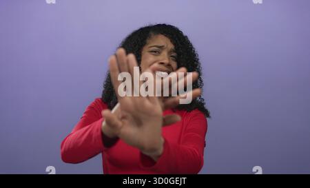 African american woman with extended hand makes a stop gesture in studio against purple background; rejection. Stock Photo