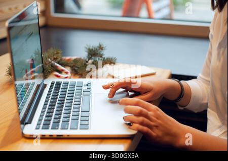 Unrecognizable woman professional types on a modern laptop at a wooden desk Close-up Stock Photo