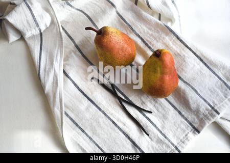 Two pears and vanilla sticks on a linen cloth Stock Photo