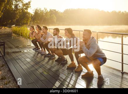 Positive Team Doing Squats In City Park Stock Photo