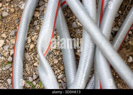 grey and red used hosepipe laying on the ground Stock Photo