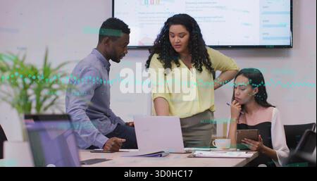 Three professionals in office wear reviewing charts on laptop and display screen in meeting room Stock Photo