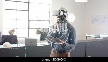 Analyzing man wearing VR headset holding tablet using holographic interface in office near hard hat Stock Photo
