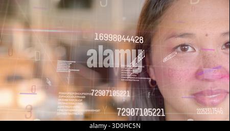 Mid adult Asian woman analyzing floating digital codes overlay in office, copy space Stock Photo