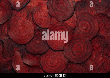 Organic red beetroot slices background. Fresh beetroot texture, close up, top view. Heap uncooked beet root cut into circular slices, dark burgundy co Stock Photo
