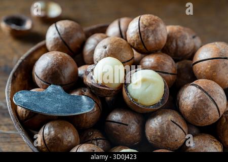 Macadamia nuts with a metal key for opening the shell in wooden bowl, close up Stock Photo