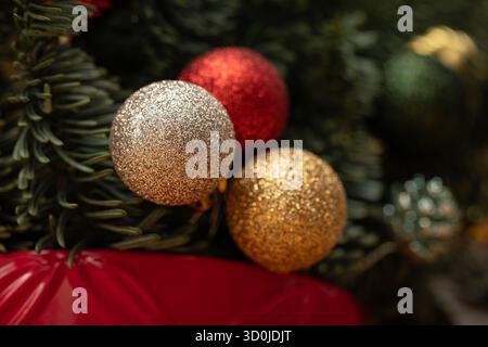 Sparkling red, gold, and silver Christmas baubles nestled in a festive fir tree. A magical close-up capturing the holiday spirit and a warm, elegant a Stock Photo