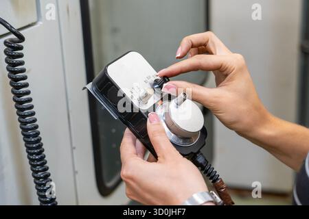 Female operator holding CNC machine manual controller Stock Photo