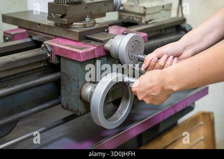 Woman operator using manual controls on metal lathe machine Stock Photo