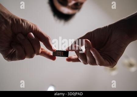 Low-angle view of man replacing sim card in mobile phone, providing efficient and reliable technical support to customer. Stock Photo