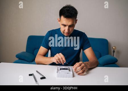 Portrait of technician male assembling wi-fi module using specialized tools at home office desk, focusing on intricate components and ensuring proper Stock Photo
